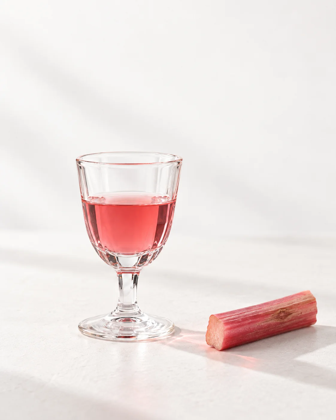 A 40 ml serve of Rhubarb in a small stemmed glass, colour against the light